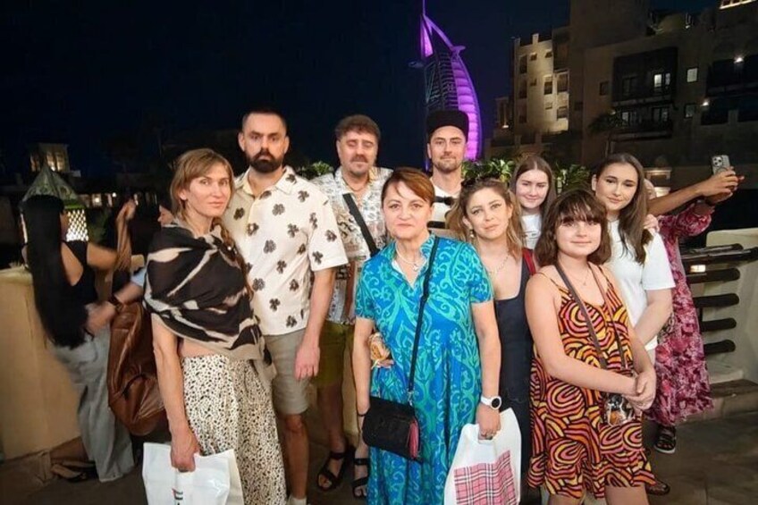 A group of people posing for a photo in an urban setting with a distinctive building in the background. 4