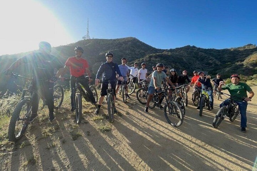 Un grupo de ciclistas en una carretera pavimentada, con un paisaje montañoso al fondo. 5