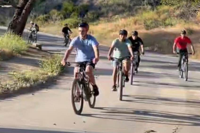 Ciclistas en un camino pavimentado rodeado de hierba seca y árboles. 4