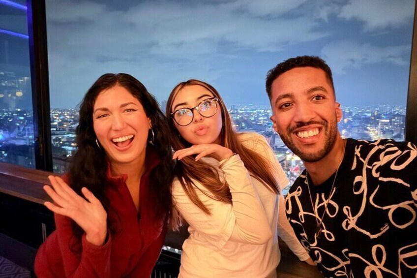 Three people posing in front of a cityscape backdrop. 3