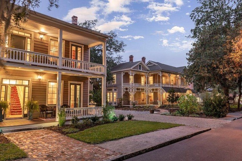 A two-story house with a porch, a well-maintained lawn, and a brick pathway. 1