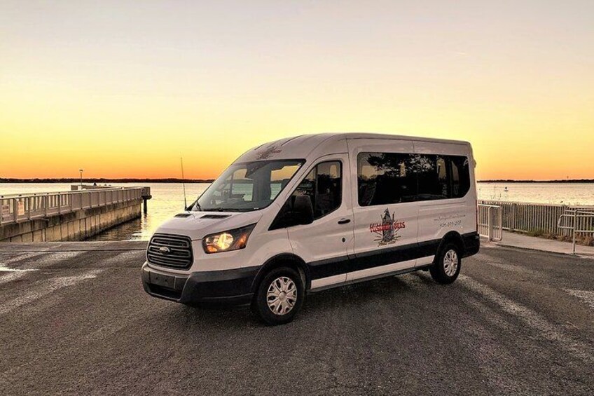 A white van parked on a waterfront with a sunset in the background. 4