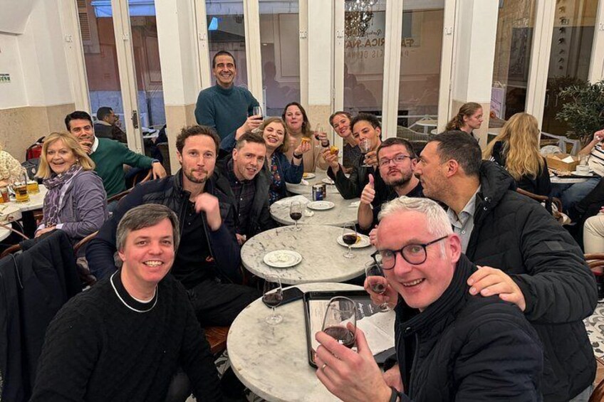 Eine Gruppe von Menschen sitzt in einem Café an runden Tischen. 3