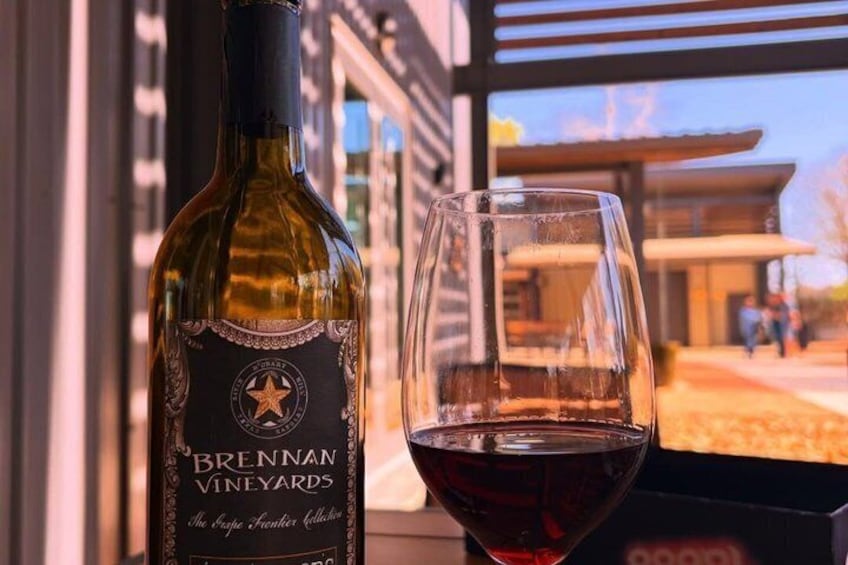 A bottle of Brennan Vineyards wine and a glass of red wine on a table. 2