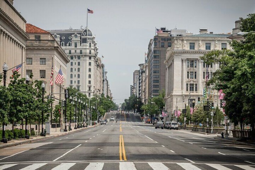 A wide city street lined with historic buildings and American flags. 3