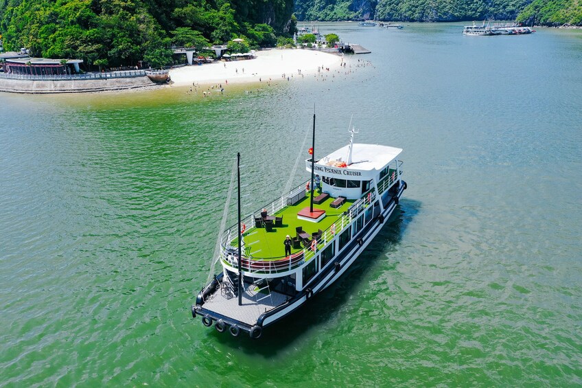 A river cruise boat with a green deck and passengers. 1