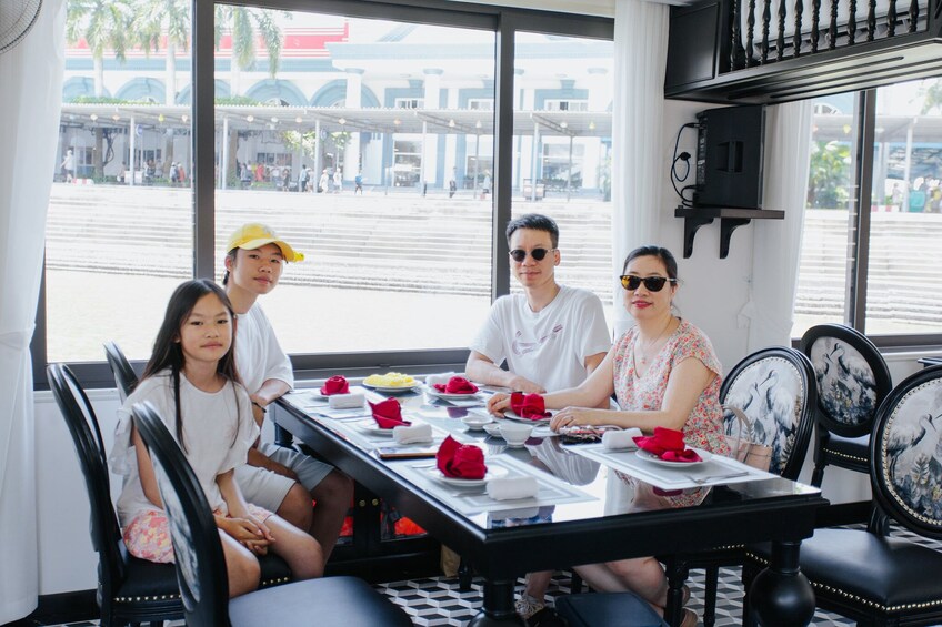 A group of people dining at a table with a view of a building and palm trees outside. 3