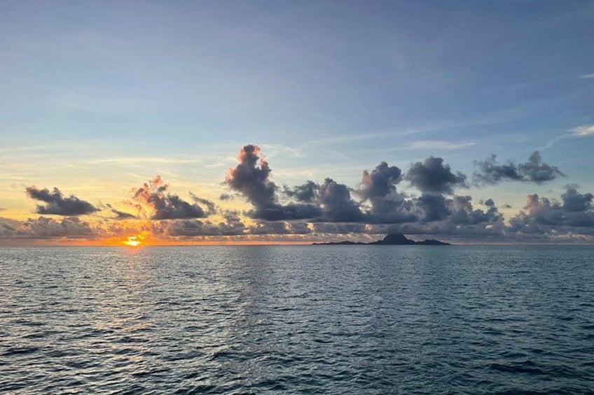 A sunset over a calm sea with a distant island. 3