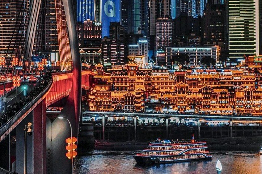 Une vue urbaine avec des bâtiments illuminés, un pont et une rivière où navigue un bateau. 5