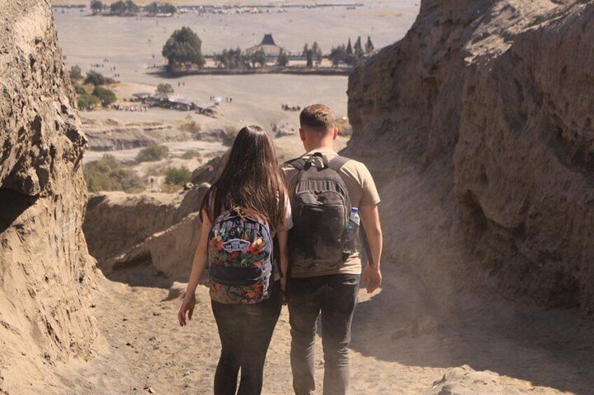 Two people walking through a canyon with a river in the background. 5