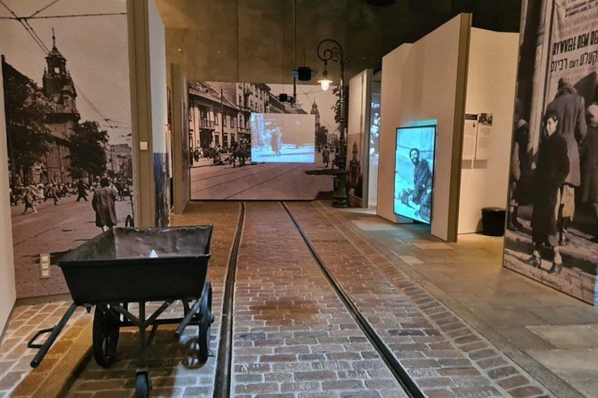A museum corridor with a vintage tram, historical posters, and a digital display. 2