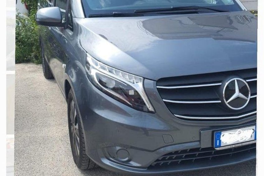 En grå Mercedes-Benz-bil står parkerad på en asfalterad yta. 2