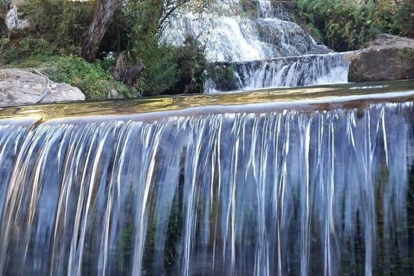 Een waterval die over rotsen stroomt in een bebost gebied. 4