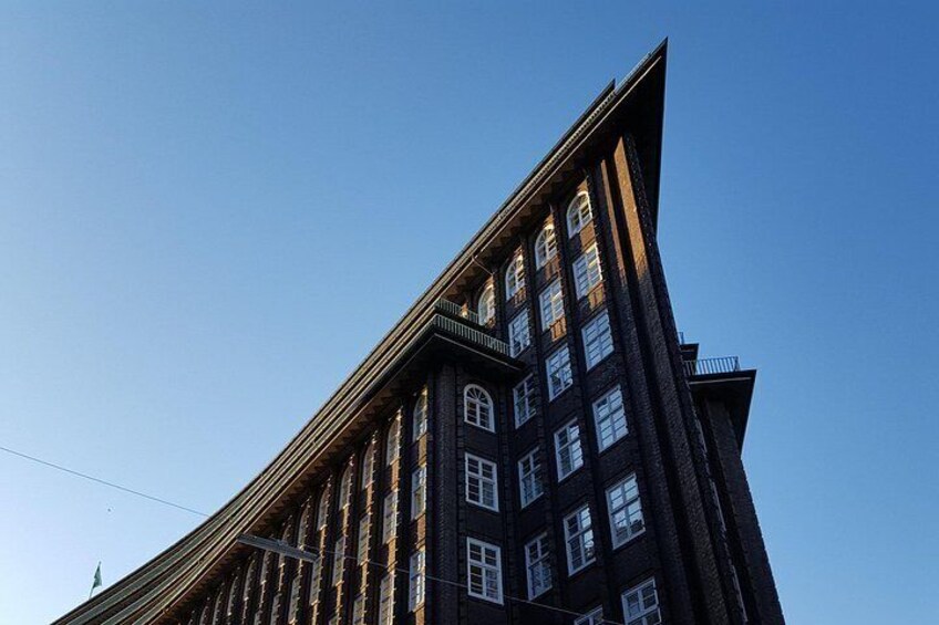 Un bâtiment haut, de couleur sombre, doté de nombreuses fenêtres et d’un toit en pente. 1