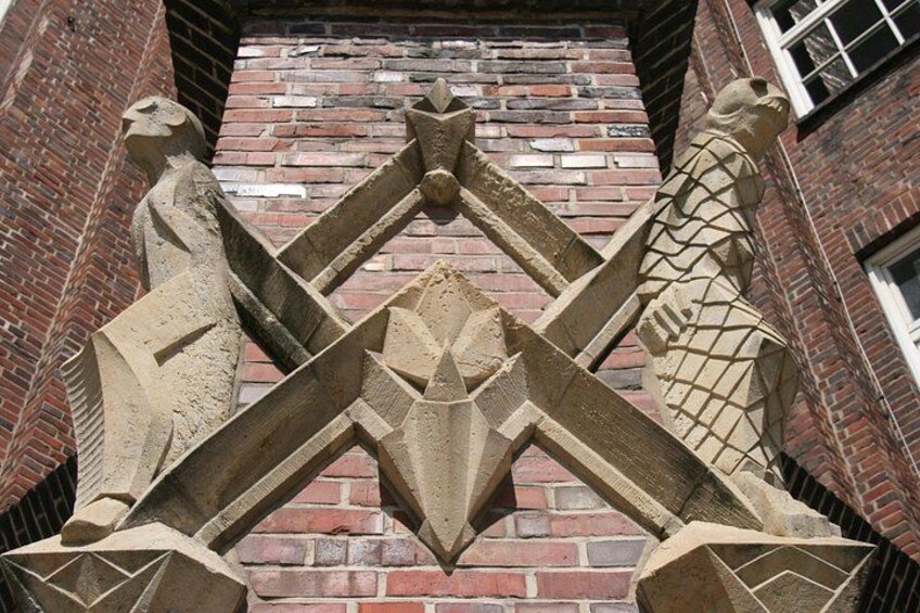 Une gargouille en pierre, ornée de motifs géométriques, sur un bâtiment en briques. 4