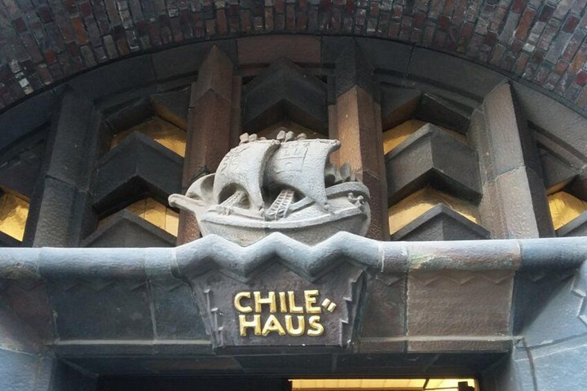 Une sculpture représentant un navire en pierre, avec l’inscription « CHILE HAUS » sur la façade d’un bâtiment. 2