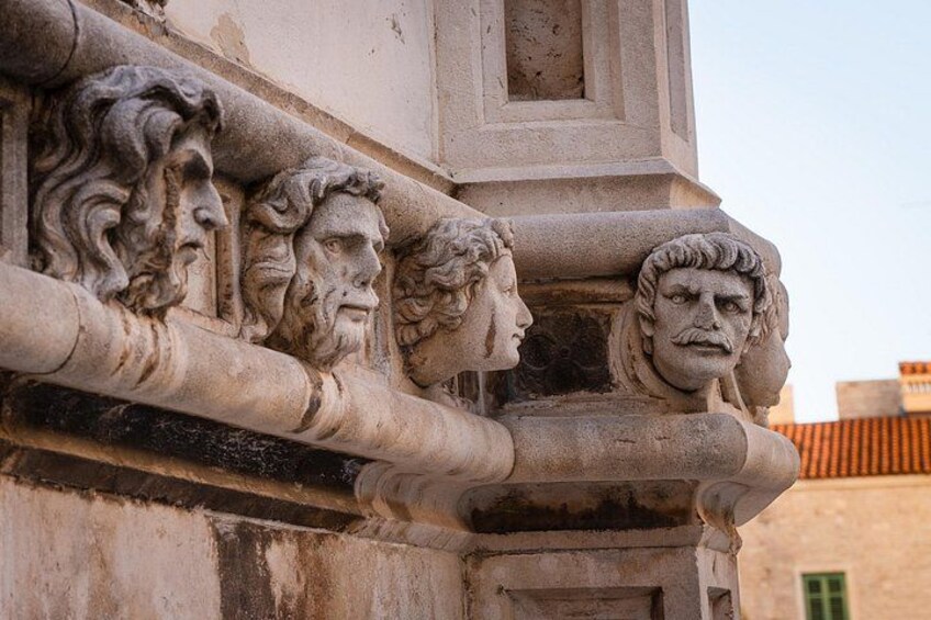 A stone facade with carved human heads and a rectangular window. 3