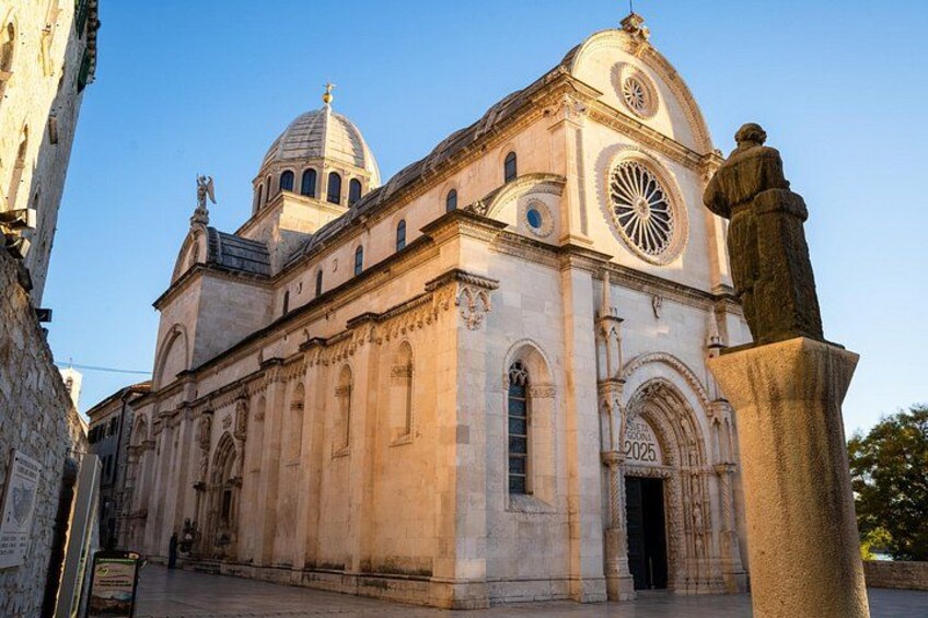 A historic church with a dome, arched windows, and a statue. 1