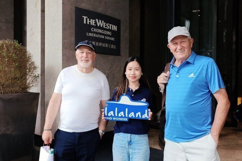 Trois personnes se tiennent devant un bâtiment sur lequel on peut lire l’inscription : « The Westin Chongqing Liberation Square ». 3