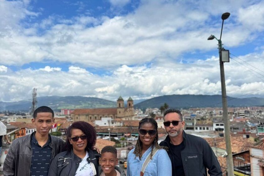 A group of people standing on a rooftop with a cityscape and mountains in the background. 2