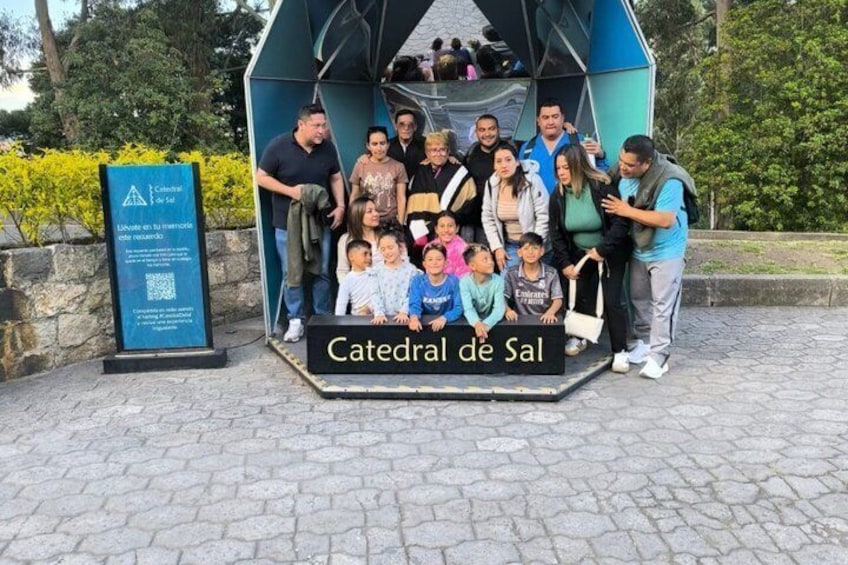A group of people posing in front of a blue structure labeled 'Catedral de Sal' with a QR code and a sign. 5
