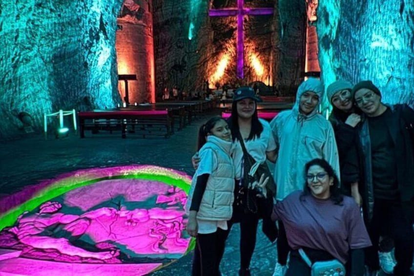 A group of people in a cave with colorful lighting and a large circular pattern on the ground. 4
