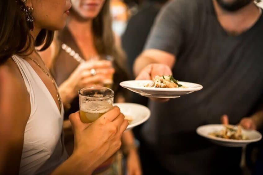 Eine Person hält einen Teller mit Essen und ein Bierglas. 3