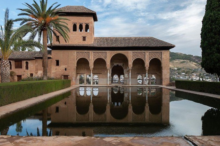 Un edificio storico con archi e una piscina che riflette la sua struttura. 2