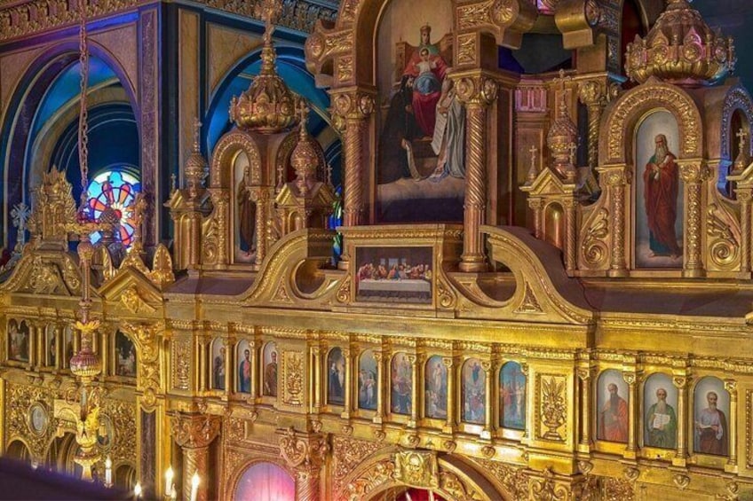 Een versierd kerkinterieur met gouden decoraties, glas-in-loodramen en religieuze schilderijen. 2