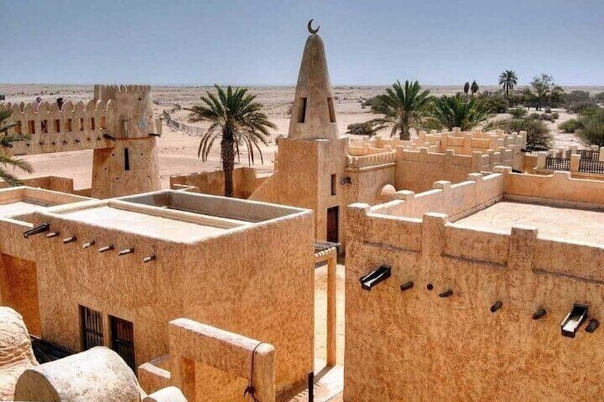 A desert landscape with traditional architecture, including a tower and fortified walls. 5