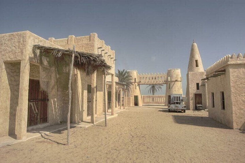 A desert landscape with traditional buildings, a large gate, and a vehicle. 4