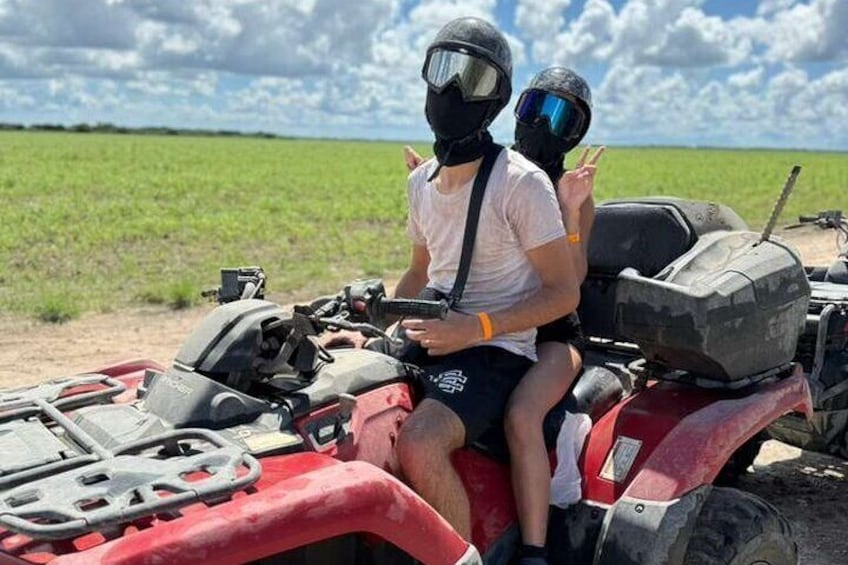 Two people on a red ATV in a field. 5