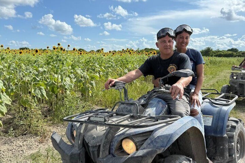 Two people on an ATV in a sunflower field. 2