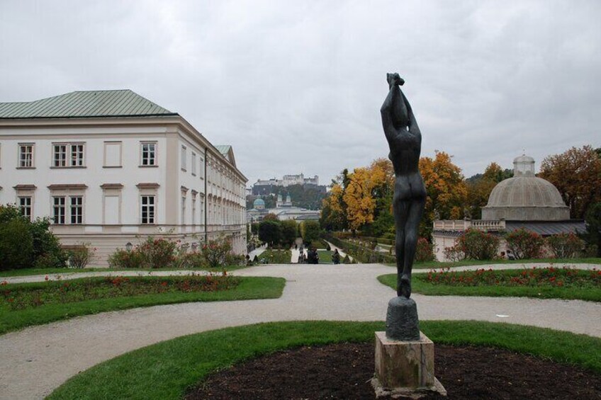 Una estatua en un parque, con un edificio y una cúpula al fondo. 2