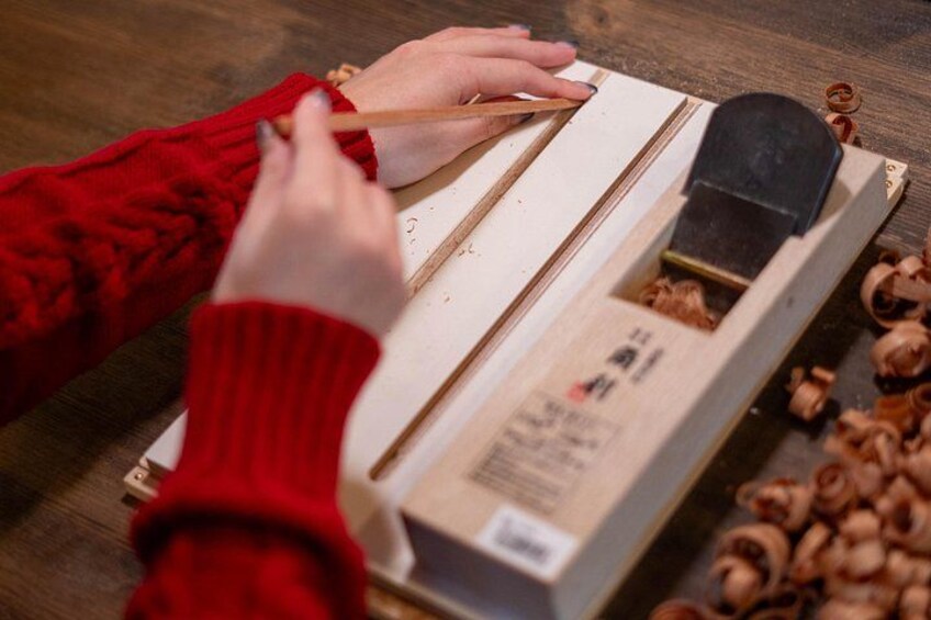 Une personne utilise un outil de coupe du bois sur une planche de bois. 1