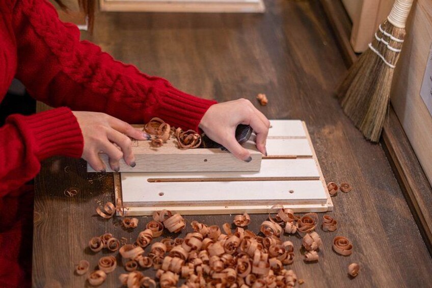 A person using a wood carving tool on a wooden board. 1