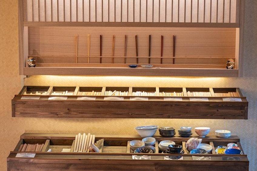Une étagère en bois avec des baguettes, des bols et des porte-baguettes. 4