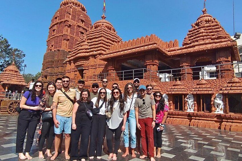A group of people standing in front of a large, intricately carved temple with multiple spires. 1