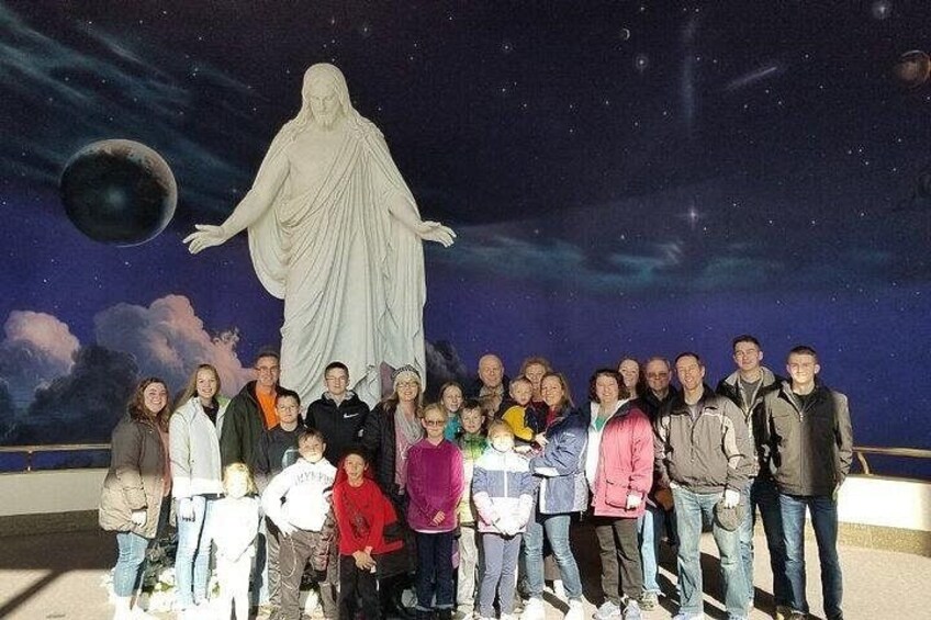 A group of people posing in front of a statue with a night sky backdrop. 1