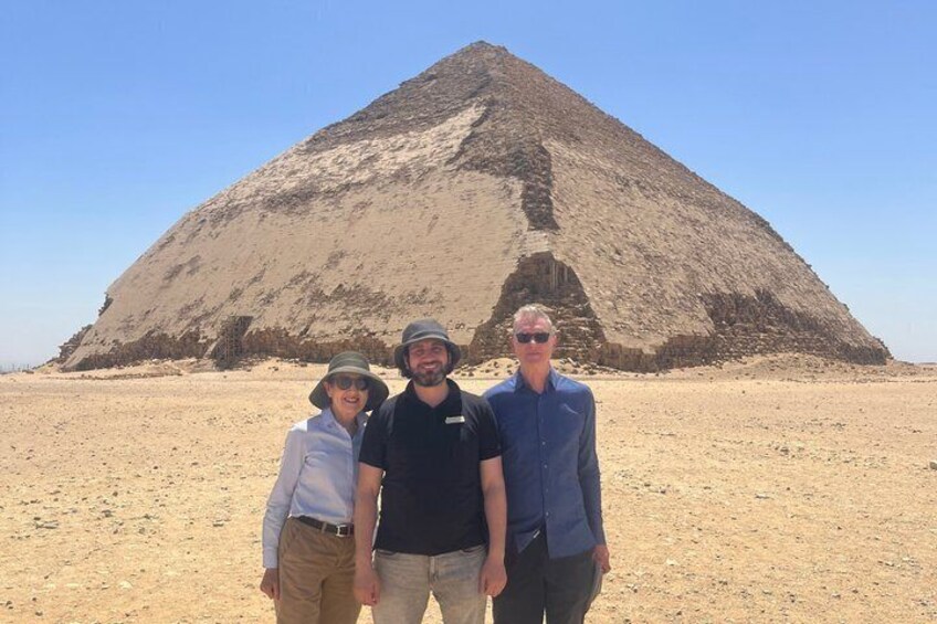 Tres personas frente a una pirámide grande en un paisaje desértico. 4