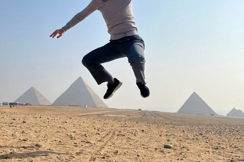 A person jumping in front of the pyramids. 2