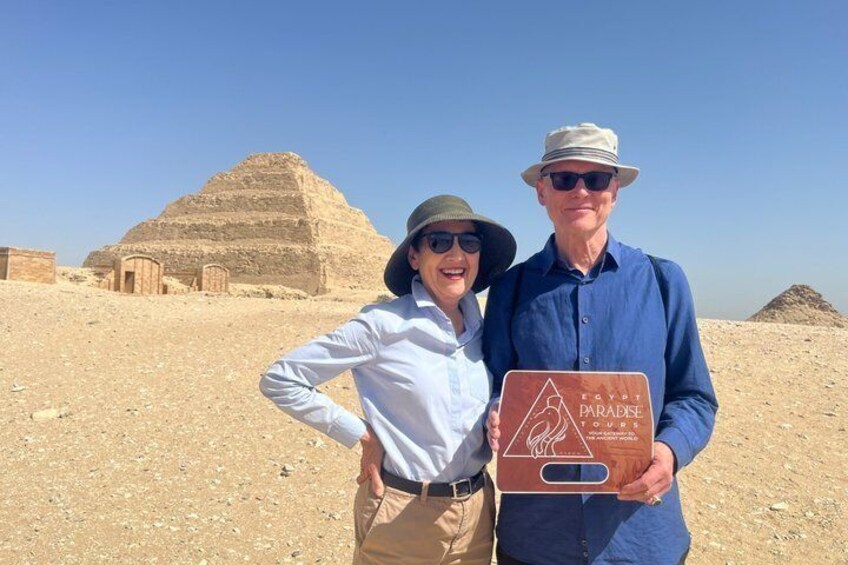 Dos personas en un desierto con pirámides al fondo. 3