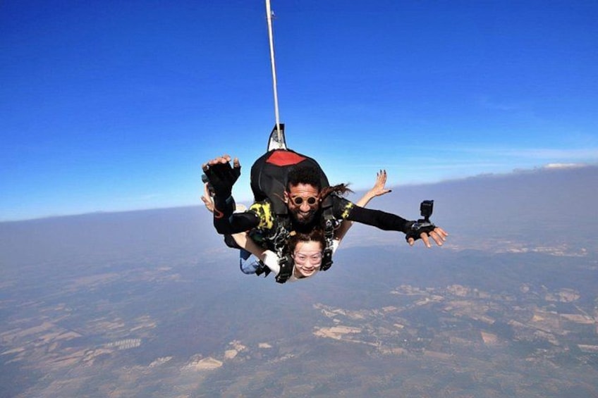A person skydiving with a parachute, high above the ground. 3