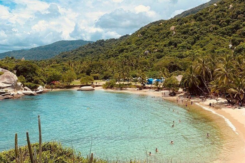 Una playa con aguas turquesas cristalinas, palmeras y montañas al fondo. 1