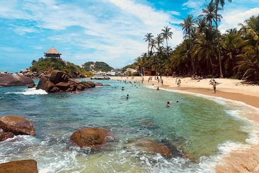 Una playa con agua cristalina, palmeras y un pabellón. 4