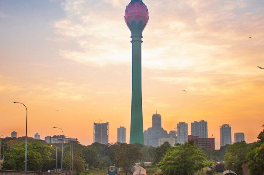 A tall tower with a spherical top, surrounded by trees and buildings in a cityscape during sunset. 2