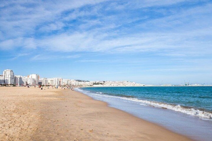 Une plage avec un ciel dégagé, un rivage sablonneux et des bâtiments en arrière-plan. 4