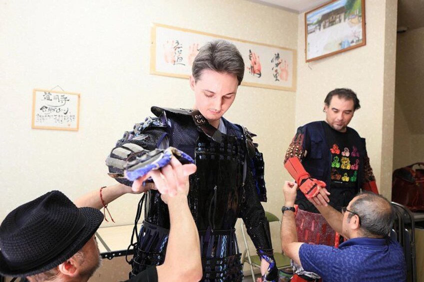 A person in a black costume with a mask, being assisted by another person. 5