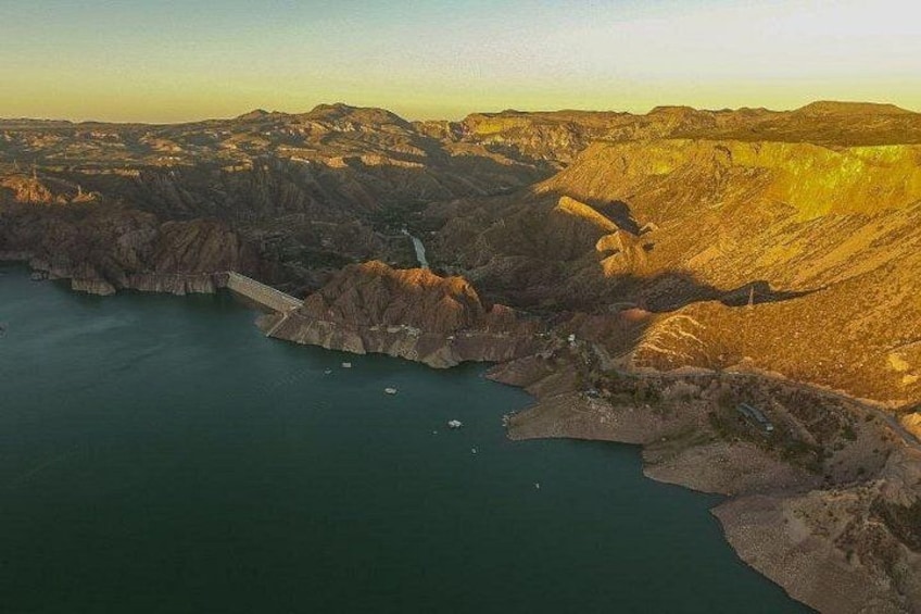A dam with a bridge, a river, and surrounding hills. 1