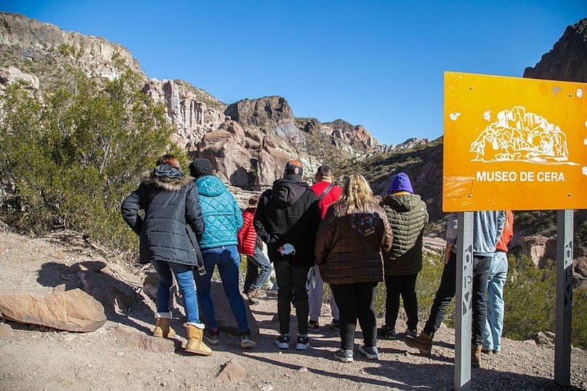 A group of people standing near a sign that reads 'MUSEO DE CERA' in a rocky outdoor setting. 5